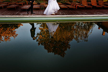 groom and bride walking beside pool during daytime thumbnail