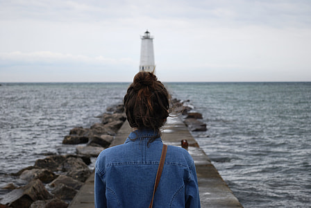 woman wearing blue denim top standing in front of white light post during daytime thumbnail