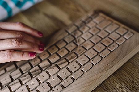 Closeup of female hands typing text on a wireless wooden keyboard thumbnail