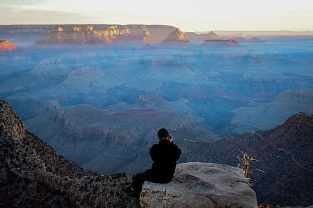 person sitting on boulder facing mountains thumbnail