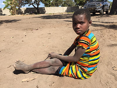 boy sitting on sand near vehicle during day thumbnail