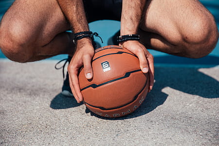 A young player holding a basketball with his palms on the ground in the day time thumbnail