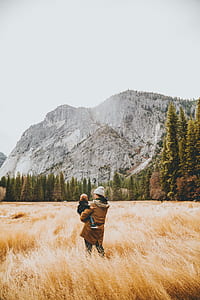 woman carrying child under cloudy sky during daytime thumbnail
