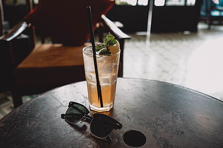 black framed Clubmaster-style sunglasses beside drink on table thumbnail