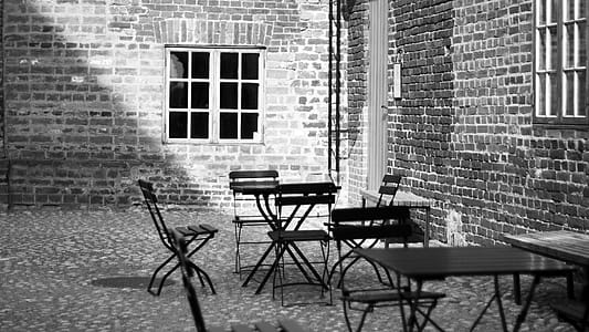 Grayscale Photo of 4-piece Dining Set Near Concrete Building thumbnail
