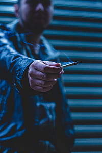 shallow focus photo of man holding blunt thumbnail