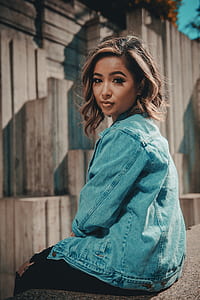 woman wearing blue denim jack sitting on concrete thumbnail