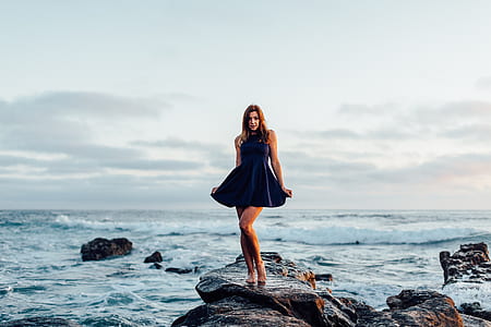 woman standing on rock near body of water during daytime thumbnail