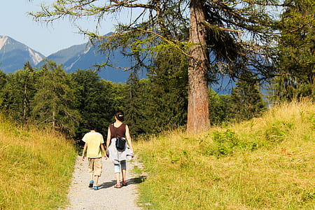 woman holding the hand of the child near tree thumbnail