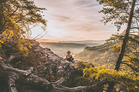 woman in brown cowboy hat sitting on brown rock thumbnail