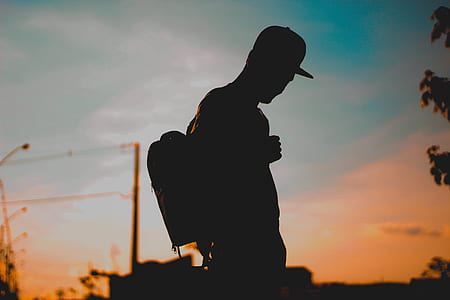 silhouette of man carrying backpack during sunset thumbnail