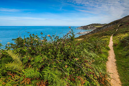 body of water near mountain under blue sky at daytime thumbnail
