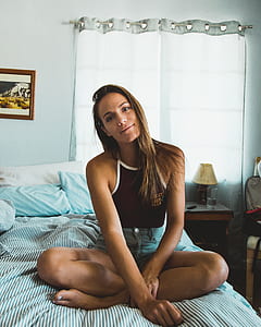 woman squatting on bed near nightstand thumbnail
