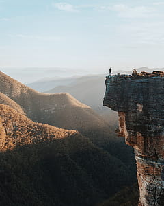 person standing on cliff during sunrise thumbnail
