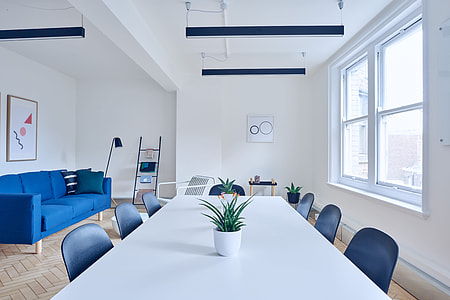 empty room with white wooden long table near blue suede 3-seat sofa thumbnail