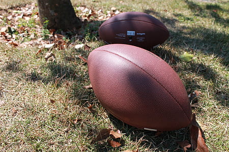 two brown football balls on ground during daytime thumbnail