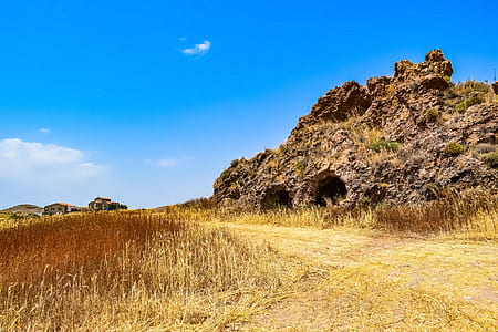 brown grass beside rock under blue sky thumbnail