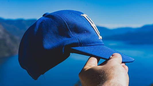 person holding blue fitted cap thumbnail
