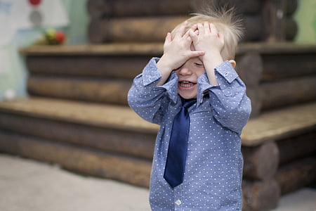 boy standing near brown desk with hands on his head thumbnail
