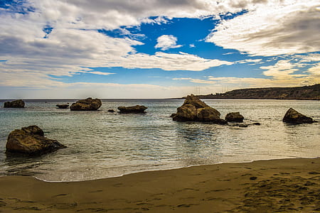 rock formation on body of water under cloudy sky during daytime thumbnail