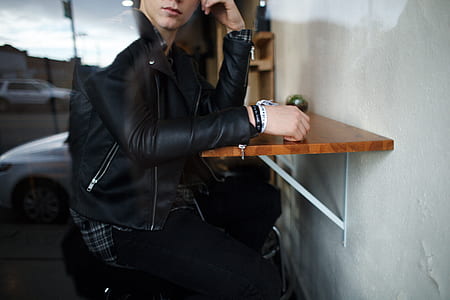 person wearing leather jacket sitting on chair thumbnail