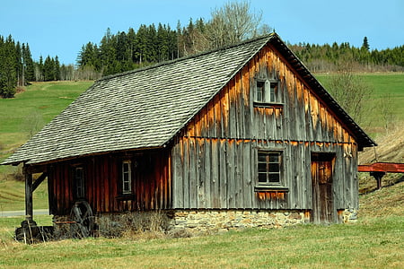 grey and brown wooden house near trees during daytime thumbnail