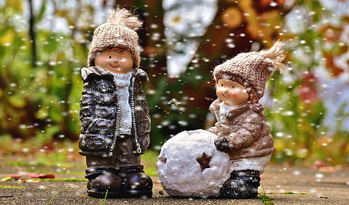 boy in black coat beside woman in brown coat holding snowball figurines wallpaper thumbnail