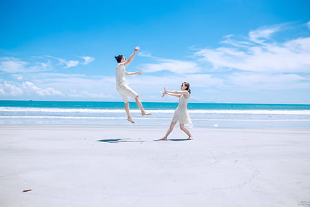 man jumping in front of woman at beach thumbnail
