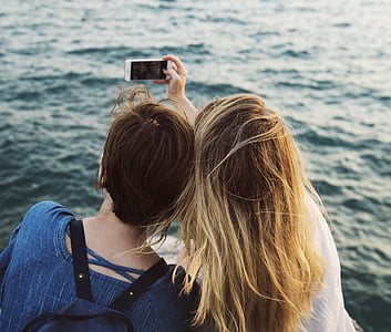 two women taking photo on front of body of water thumbnail