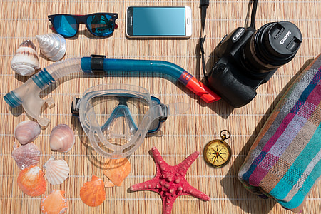 black Canon DSLR camera beside diving nozzle, diving goggles, silver Samsung Android smartphone and seashells thumbnail