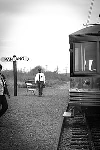 Grayscale Photo of Man Walking Near Train thumbnail