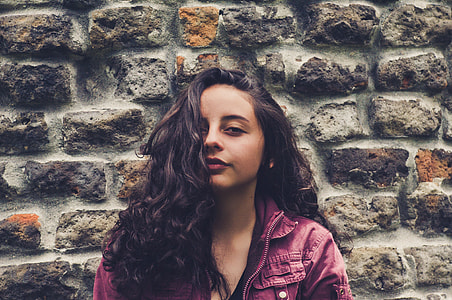 woman wearing purple zip-up jacket near concrete brick wall thumbnail