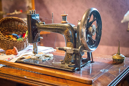 black treadle sewing machine beside gray wall thumbnail