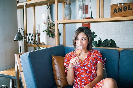 Woman Wearing Red, Purple, and Pink Floral V-neck Cap-sleeved Dress Drinking Through Clear Wine Glass thumbnail