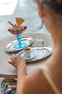 Woman Sitting on Chair While Her Left Hand Beside Coffee Mug on Gray Tray thumbnail