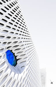 white concrete building with round blue glass window thumbnail