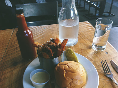 hamburger on plate beside water and ketchup bottle thumbnail