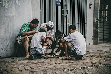 three men watching two men playing board game on street during daytime thumbnail