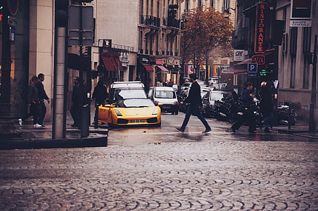man crossing road near yellow car thumbnail