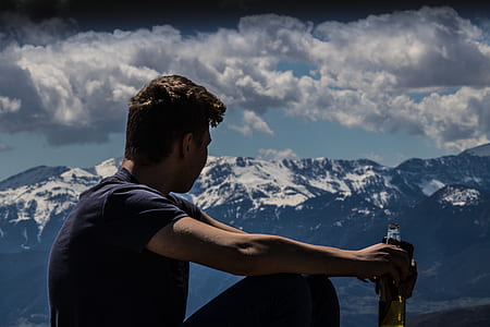 man wearing blue crew-neck T-shirt while holding clear glass bottle thumbnail