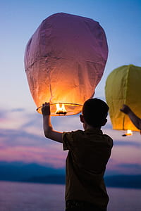 boy in brown shirt holding white fire lantern thumbnail