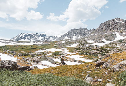 person walking on grass field near mountains thumbnail