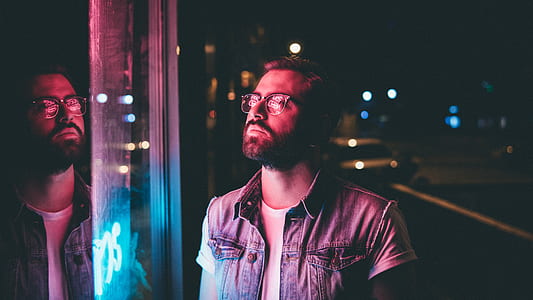 man looking at glass with lights beside the street thumbnail