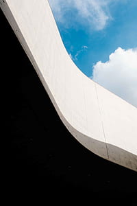 low angle photography of white wall under white and blue skies thumbnail
