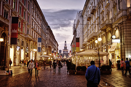 man wearing blue long-sleeved shirt walking on street surrounded with lighted buildings thumbnail
