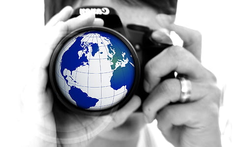 selective color photography of man holding earth globe camera thumbnail