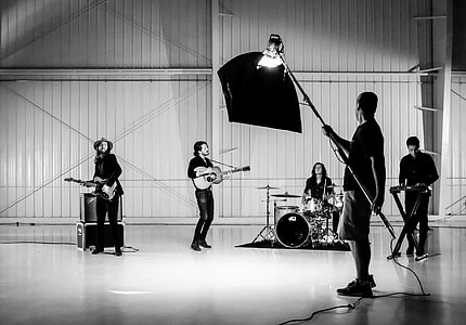 gray scale four man band playing with camera lighting thumbnail