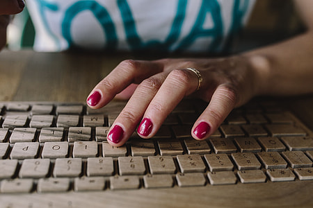 Closeup of female hands typing text on a wireless wooden keyboard thumbnail