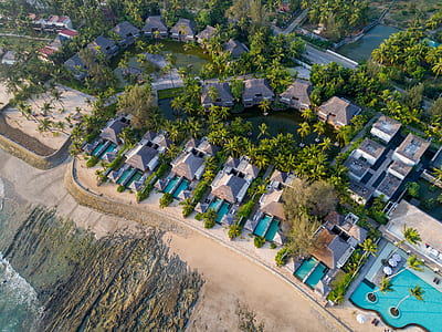 bird's eye view of resort houses and swimming pools surrounded by trees during daytime thumbnail