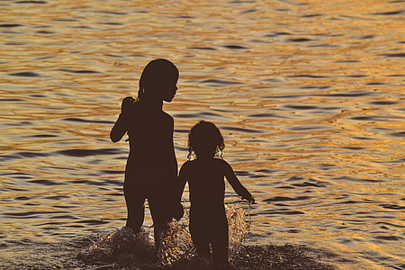 children swimming in water during sunset thumbnail